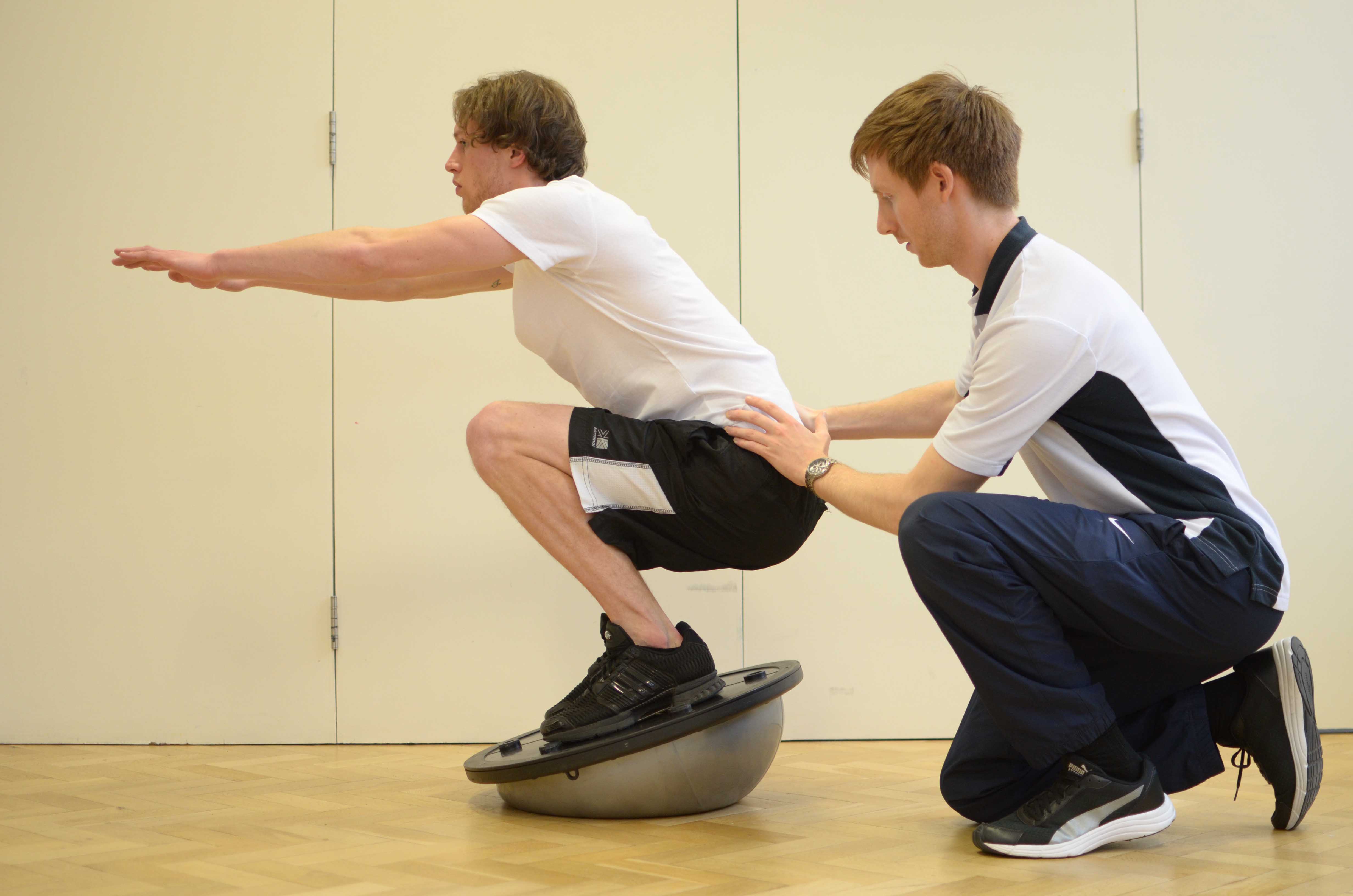 Leg strengthening and stability exercises using squats on a balance board under supervision of specialist MSK physiotherapist